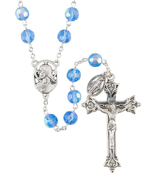 A silver-colored rosary with blue glass beads and a crucifix