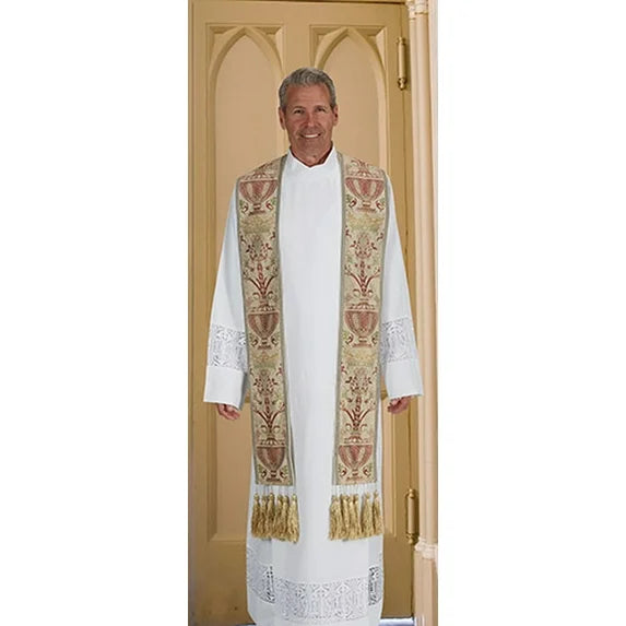 Man wearing a white robe with an embroidered stole standing in front of a door.