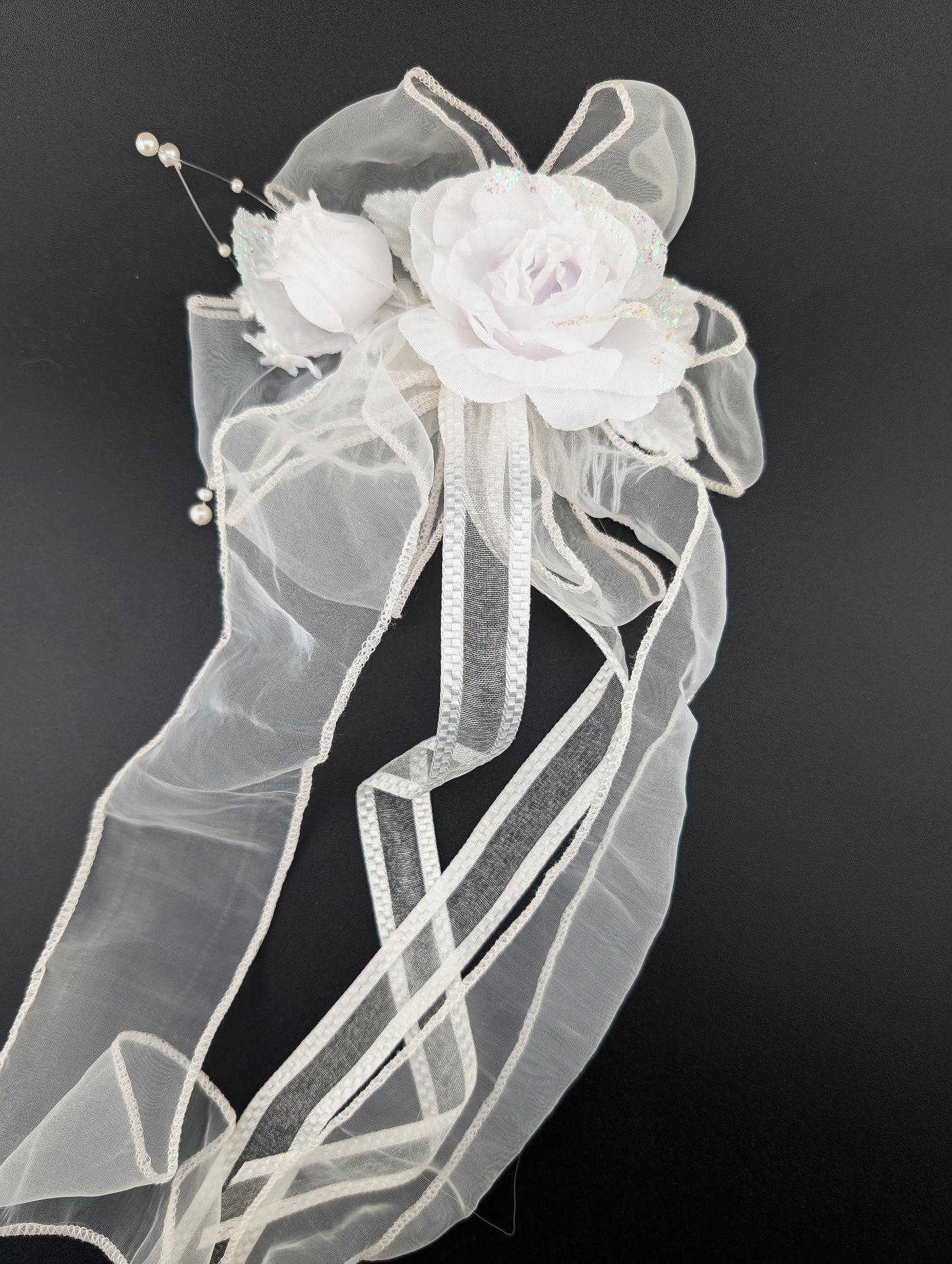 White floral hair accessory with sheer fabric on a black background