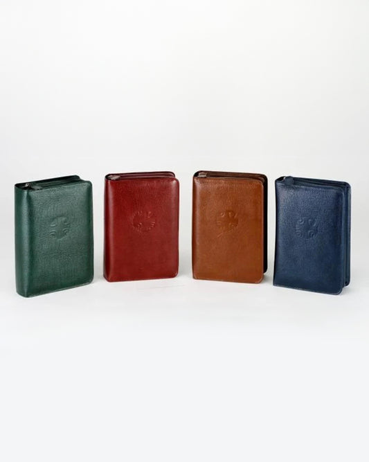 A set of four book covers made of leather, displayed in green, red, brown, and blue colors, designed for holding books with zipper closure.