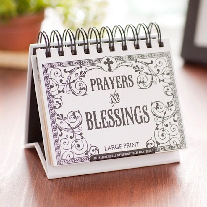 Small spiral-bound book titled 'Prayers & Blessings' on a wooden surface.