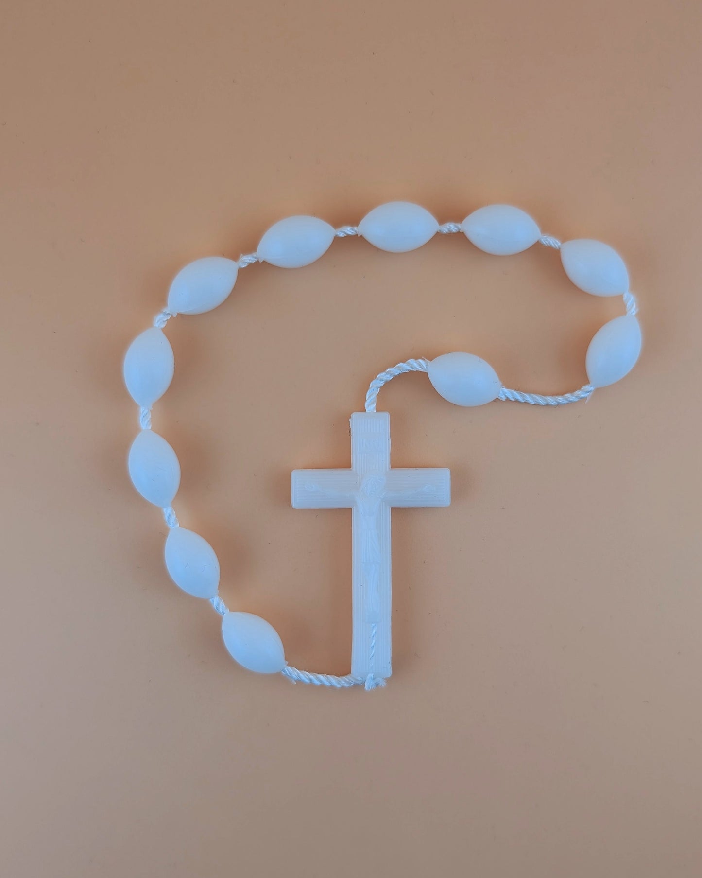 White rosary with a cross on a beige background