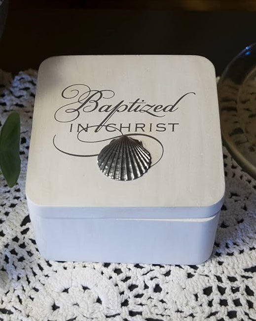 Square box with 'Baptized in Christ' text and shell design on a textured surface