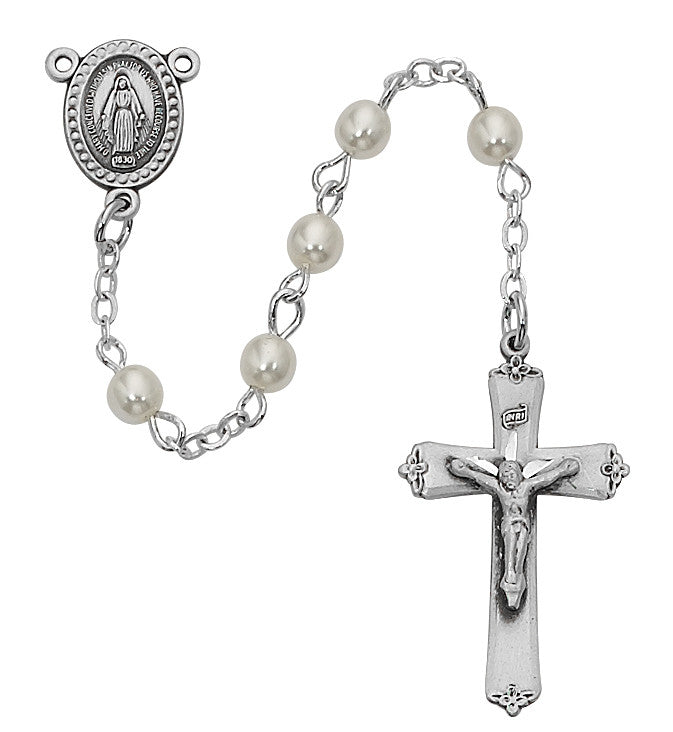 A pearl rosary with a metal centerpiece featuring a crucifix. The rosary has silver-colored metal beads and a chain, with a prominent pearl on the centerpiece.