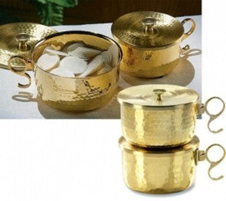 Two stacked brass ciborium pots with lids, one larger than the other, on a white surface, with an ornate design around the handles and lids.