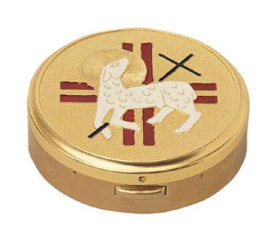 A gold-colored metal hospital pyx with a design of a lamb and cross on the lid.