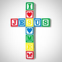 A wall-mounted resin cross with hand-painted designs in primary colors, featuring the text 'JESUS LOVES ME' and a series of vibrant, solid-colored blocks forming the cross.