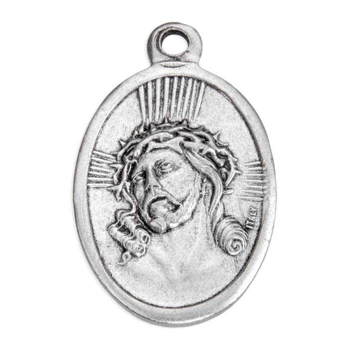 An oval silver-toned metal pendant featuring a relief carving of Jesus Christ's face wearing a crown of thorns, with radiating light lines and a hanging loop at the top, shown on a plain white background.
