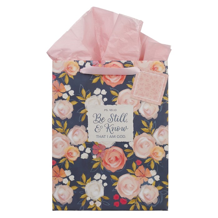 Floral gift bag with pink tissue paper and motivational tag on a white background