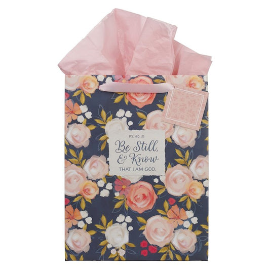 Floral gift bag with pink tissue paper and motivational tag on a white background