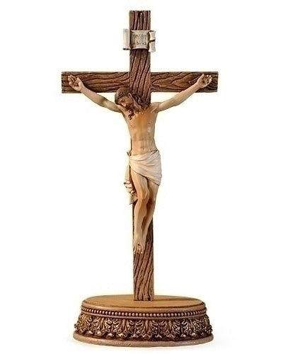Statue of a crucified figure on a cross with detailed base on a white background
