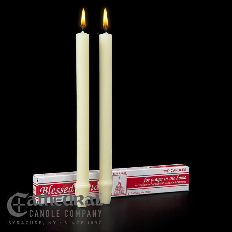 Two lit candles with their packaging on a black background, featuring the Cathedral Candle Company branding.