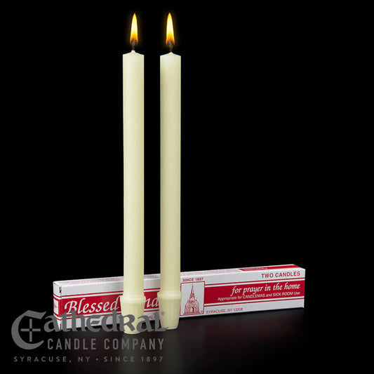 Two lit candles with their packaging on a black background, featuring the Cathedral Candle Company branding.