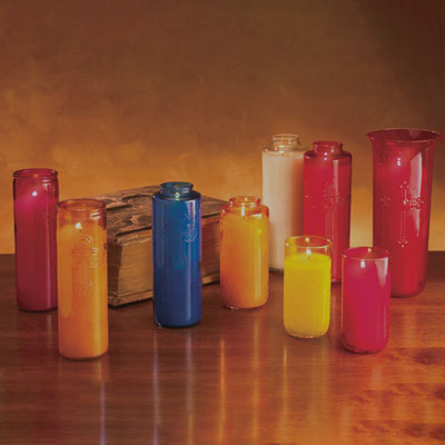 A set of colorful glass jar candles in various sizes, including pink, orange, blue, yellow, and red, arranged on a wooden table against a warm brown background.