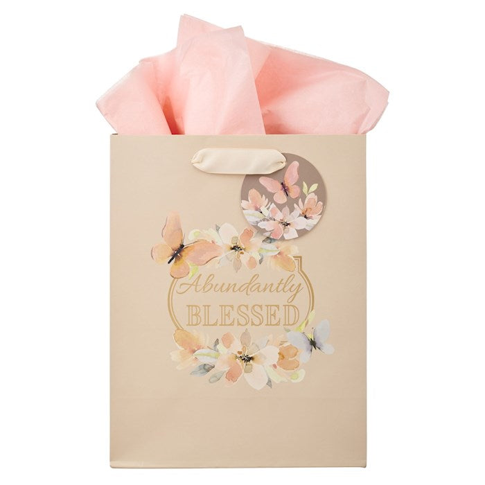 Gift bag with floral design and 'Abundantly Blessed' text, pink tissue paper inside.