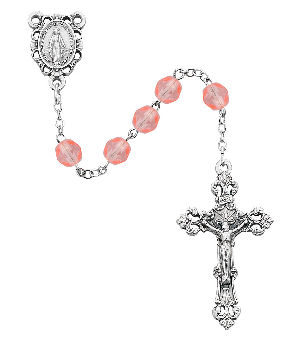 A rosary featuring faceted coral-pink beads on a silver-tone chain, with an ornate silver medal of the Virgin Mary at one end and a matching silver crucifix at the other, shown on a plain white background.