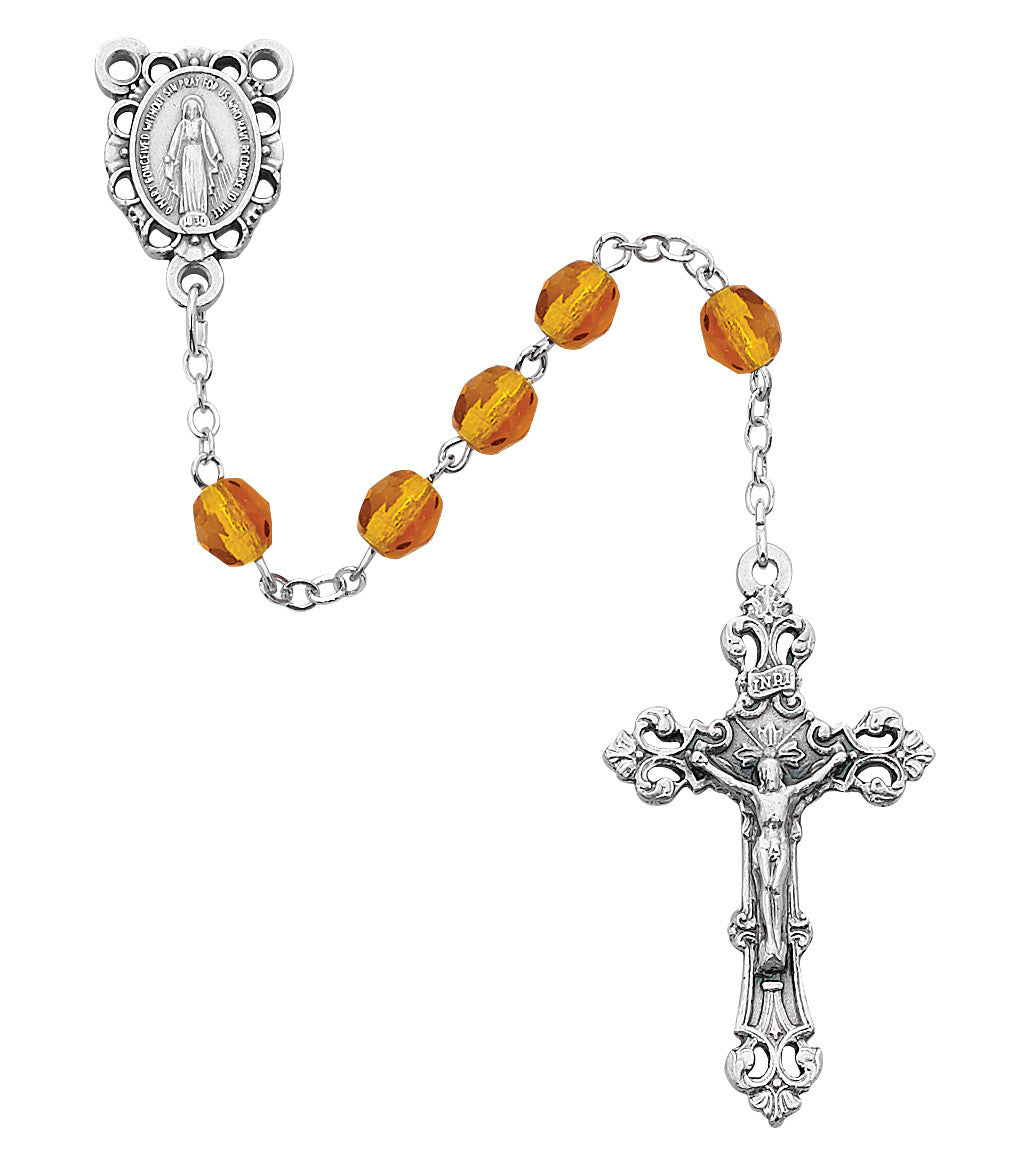 Silver rosary with amber beads on a white background