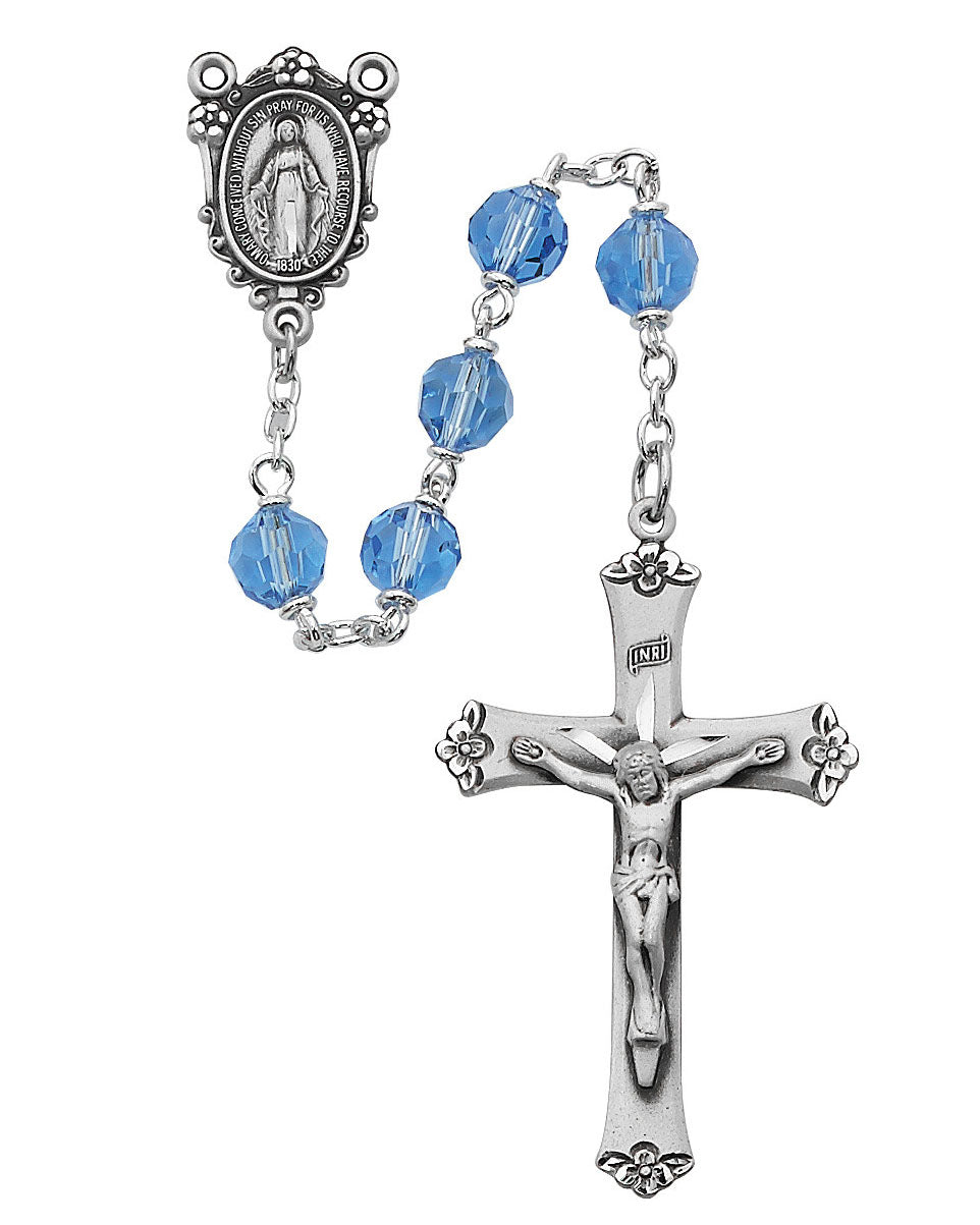 Rosary with blue beads and silver crucifix on a white background