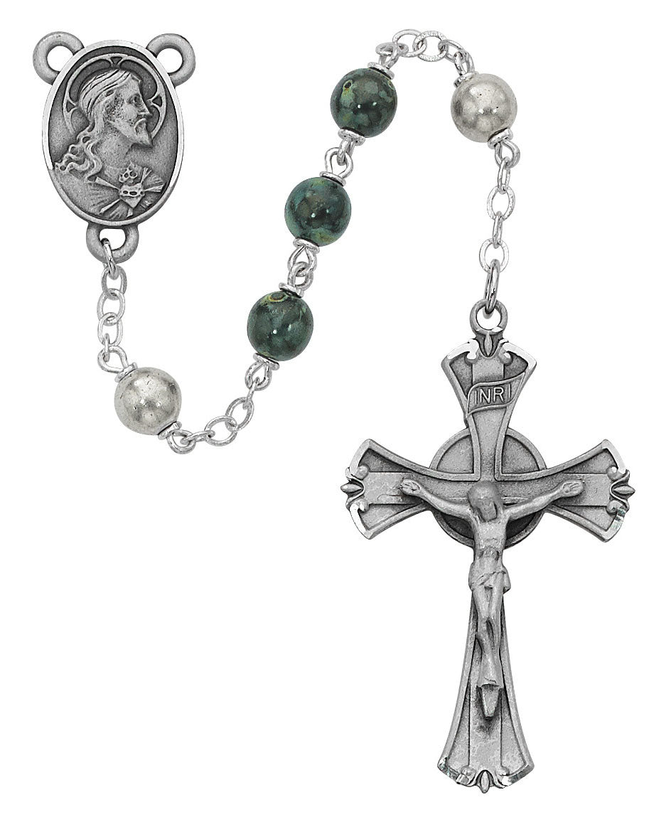 Rosary with green beads and silver cross on a white background