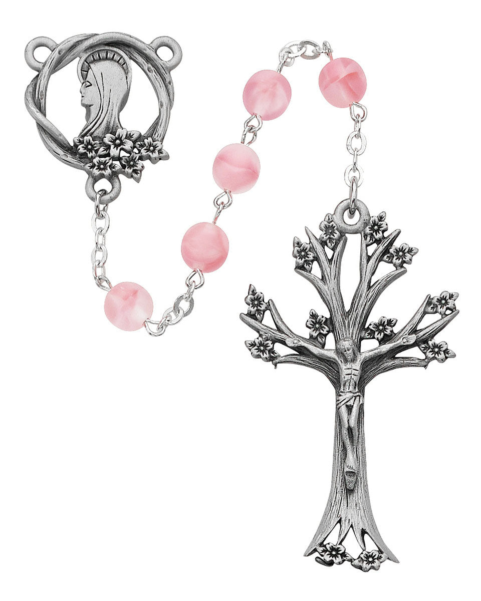 Rosary with pink beads and silver tree-shaped cross on a white background