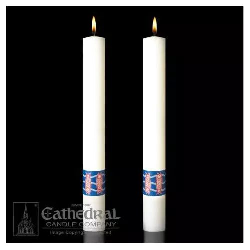 Two white candles with blue bands and lit flames on a black background, featuring the Cathedral Candle Company logo.