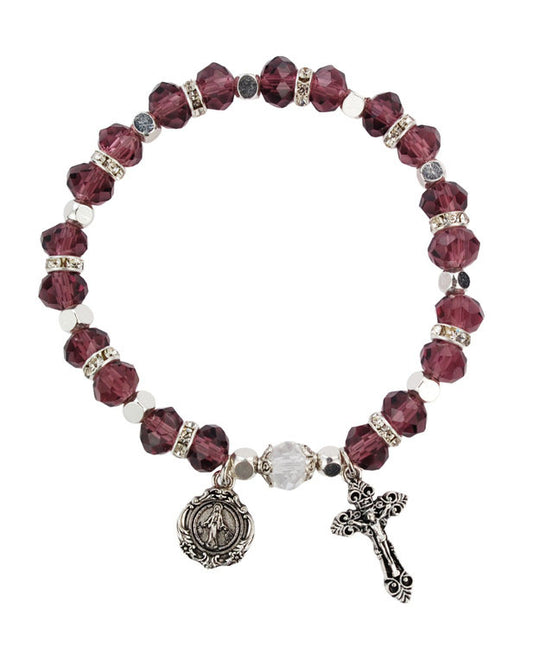 Bracelet with purple beads and religious charms on a white background