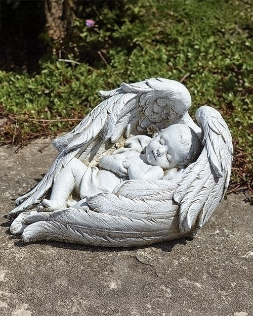 A garden statue of a sleeping baby with angelic wings.