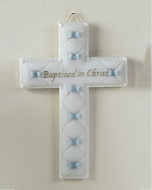 Decorative cross with 'Baptized in Christ' text on a plain wall.