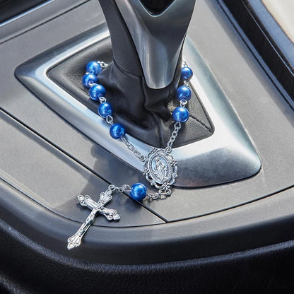 A blue beaded rosary with a silver crucifix and medallion resting on a car gear shift console.
