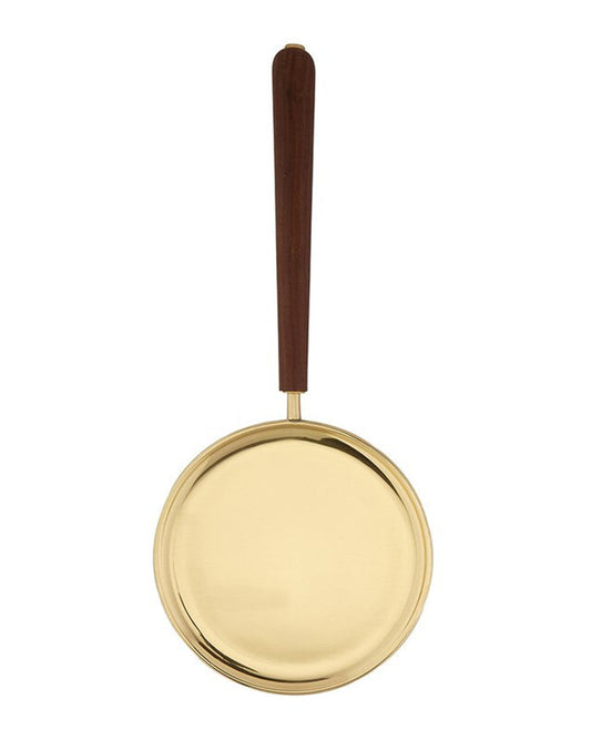 A brass paten with a straight brown wooden handle.