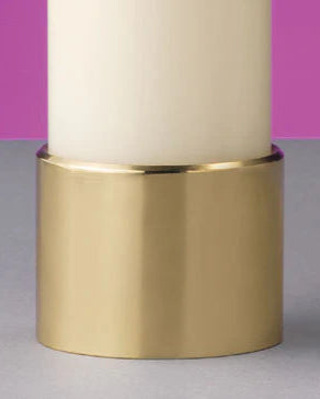 Candle with a gold holder on a gray surface against a pink background