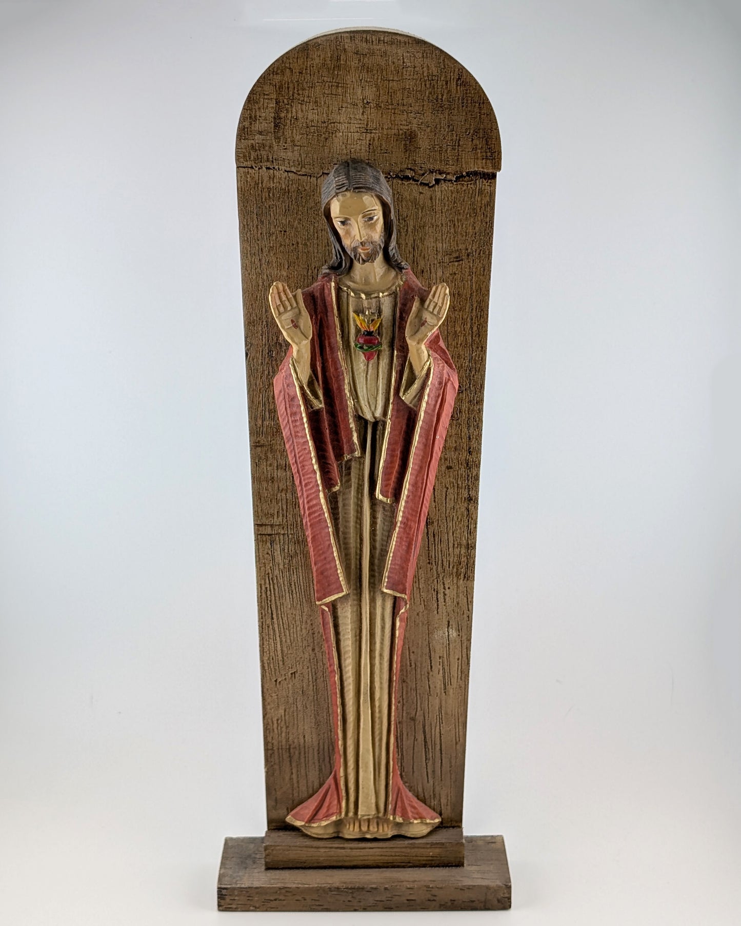 Wooden statue of a religious figure with red and gold robes on a white background