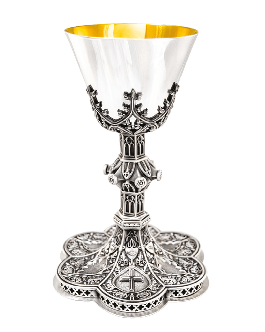 An ornate silver chalice with a polished silver-tone metal body, featuring intricate filigree detailing, a central cross, and a bright gold interior, shown on a plain white background.