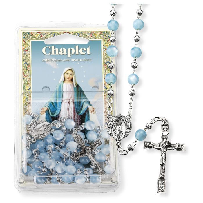 A Miraculous Medal chaplet with light blue beads and silver-colored metal components, displayed alongside its packaging which features an image of the Miraculous Medal and the Virgin Mary.
