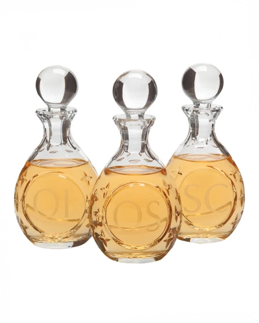 Three glass decanters with a clear liquid on a white background
