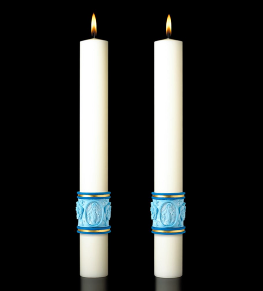 Two white candles with blue decorative bands on a black background