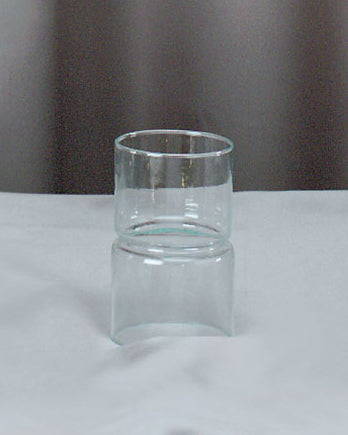 Clear glass vase on a marble surface with a neutral curtain background