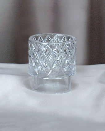 Clear glass candle holder on a white surface with a neutral background