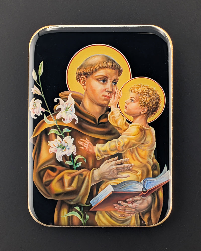 Decorative tin with an illustration of a saint holding a child on a black background