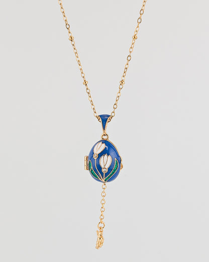 Blue pendant necklace with gold chain on a light gray background