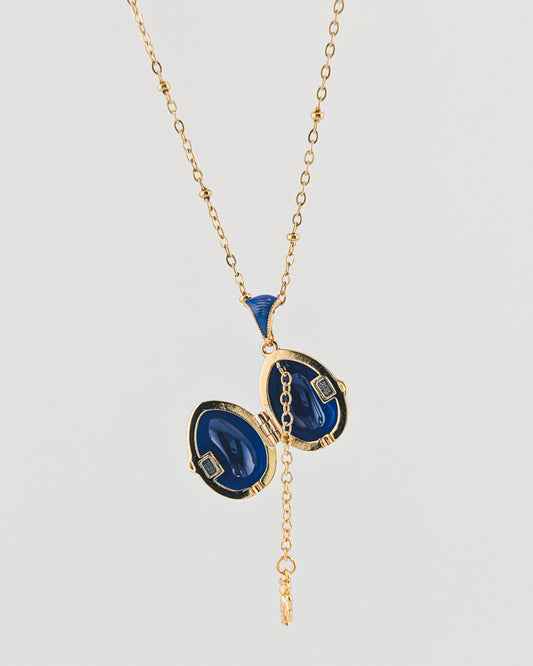 Gold necklace with blue pendant on a white background