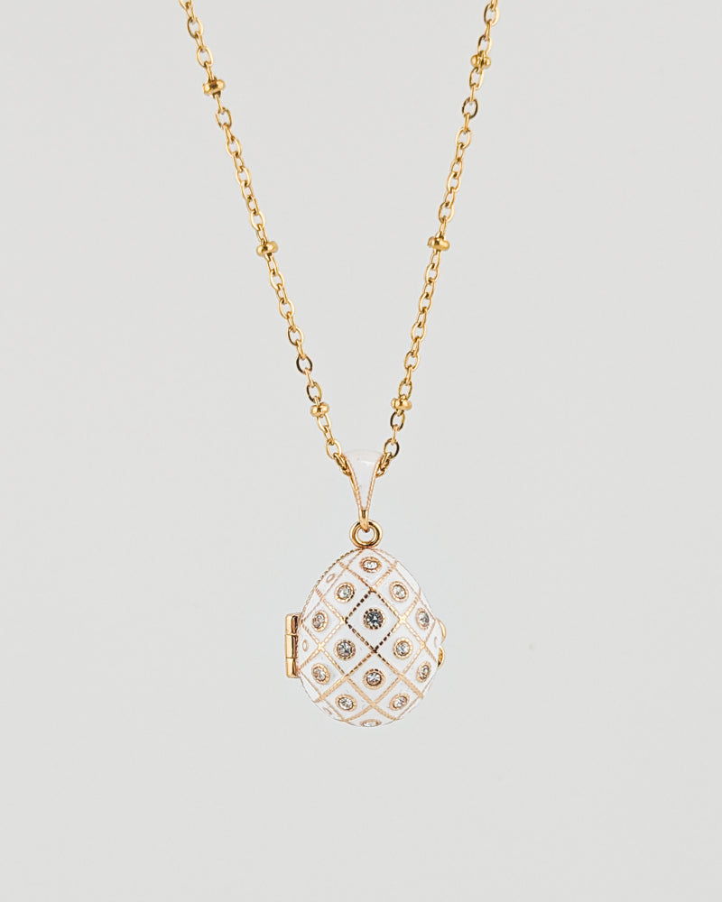 Gold necklace with a diamond-encrusted pendant on a light gray background