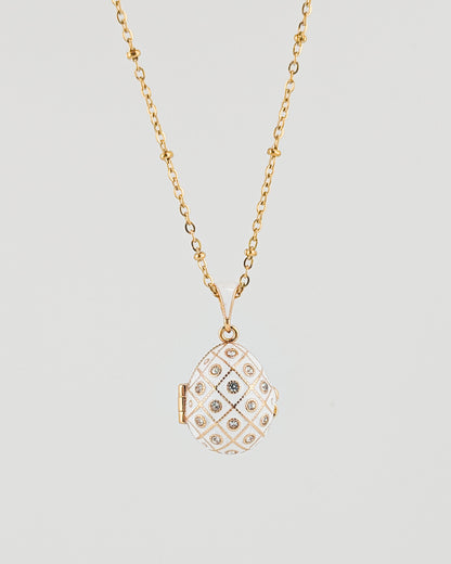 Gold necklace with a diamond-encrusted pendant on a light gray background