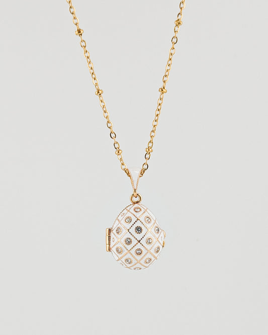 Gold necklace with a diamond-encrusted pendant on a light gray background