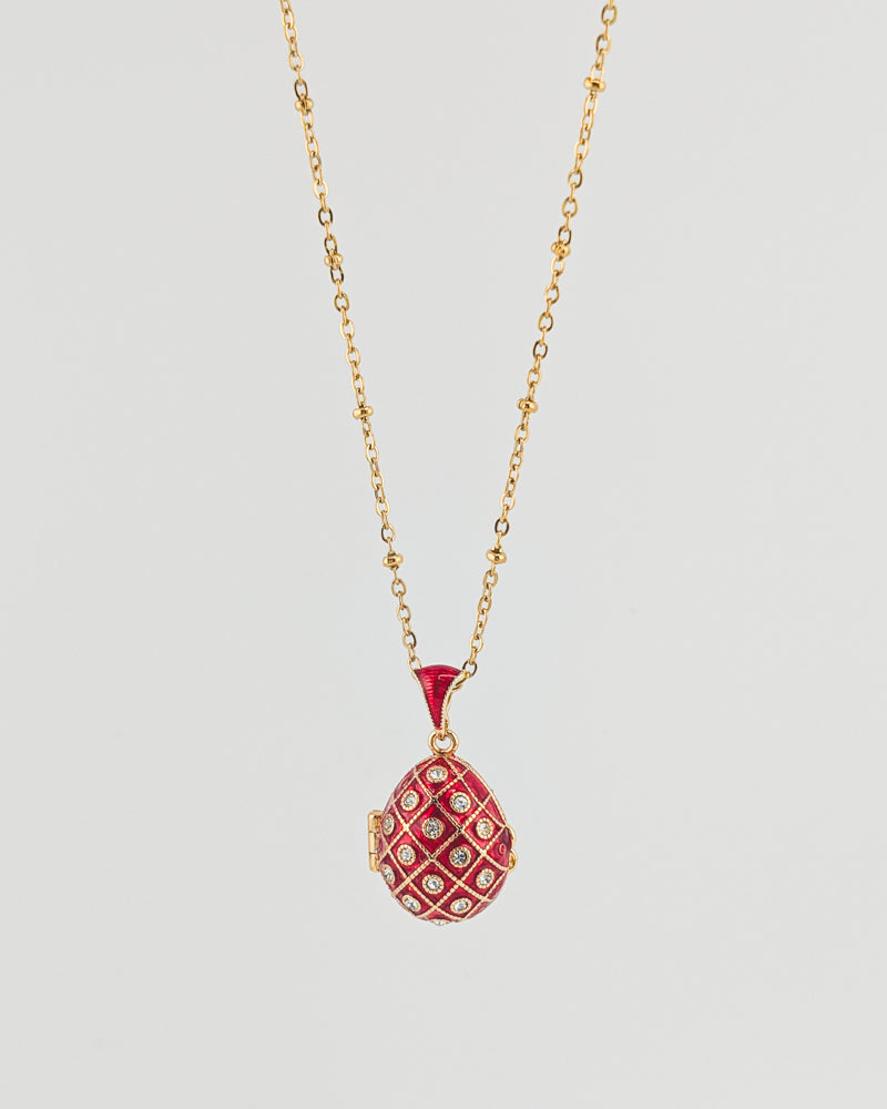 Red pendant necklace on a gold chain against a light gray background