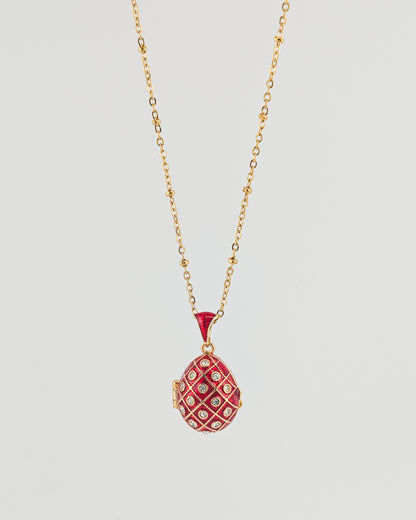 Red pendant necklace on a gold chain against a light gray background