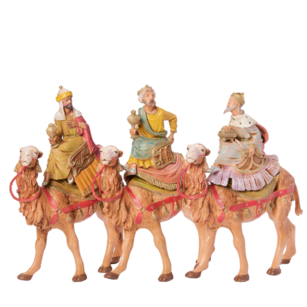 Three figurines of wise men on camels with a white background