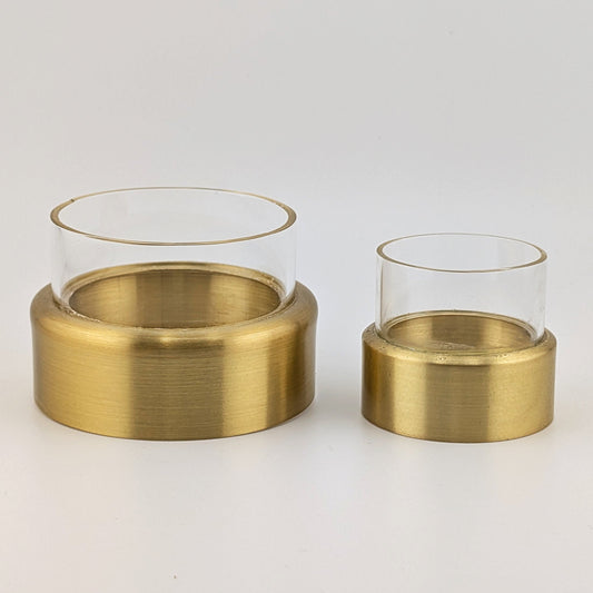 Two gold candle holders with glass containers on a white background