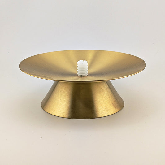 Gold metal cake stand with a white candle on a light gray background