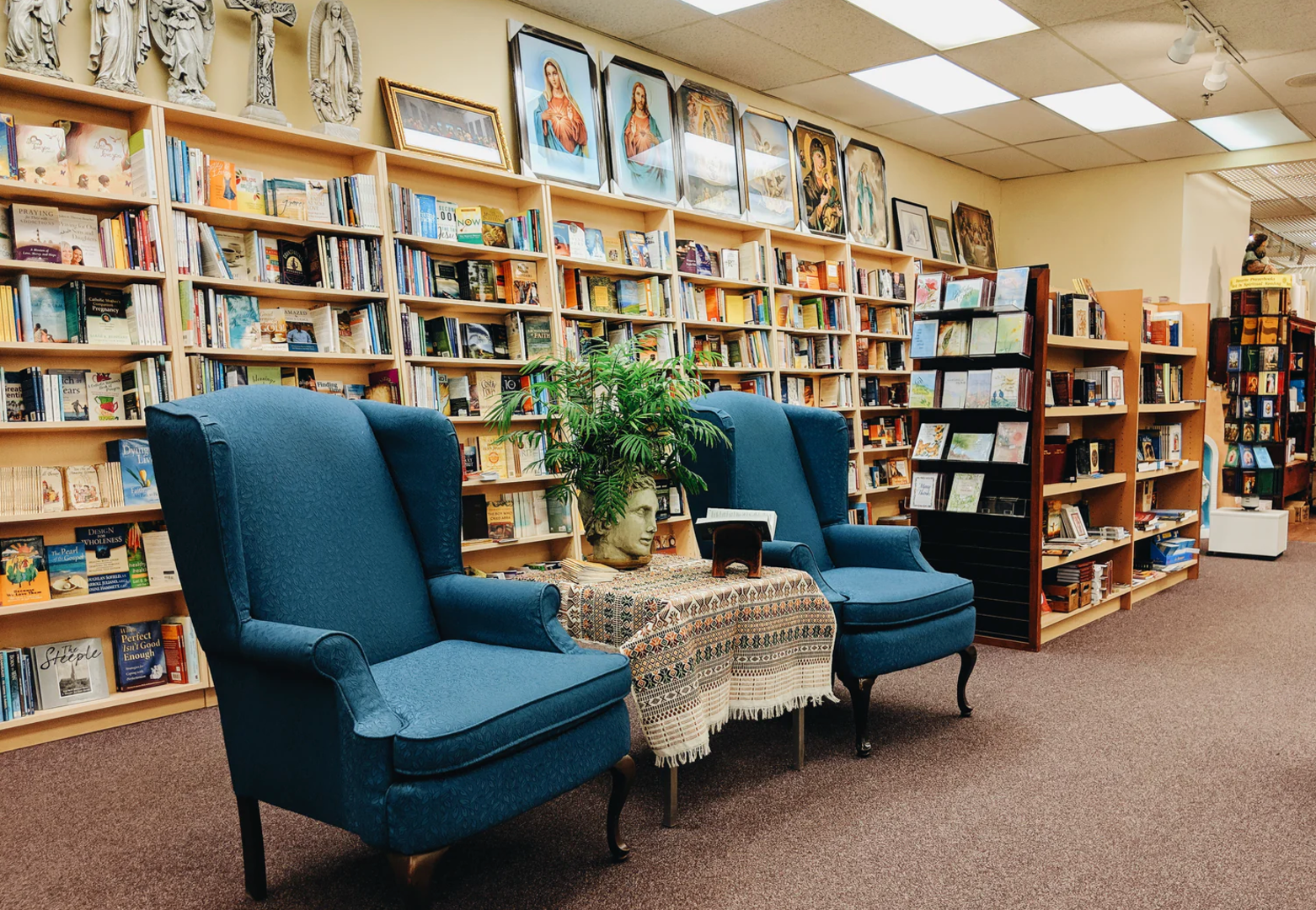 Bookstore interior with blue armchairs, table, and bookshelves.